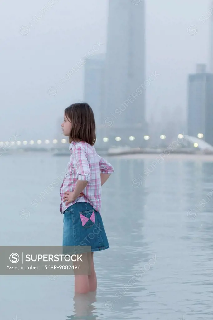 Girl wading at the beach, looking at view