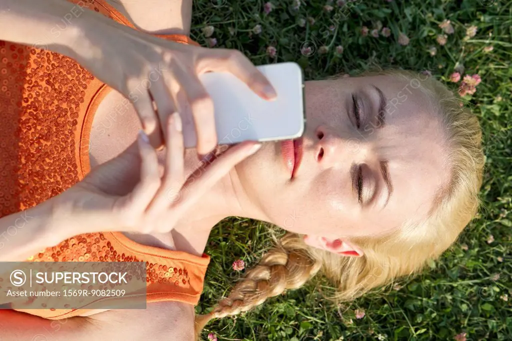 Young woman lying on grass using smartphone