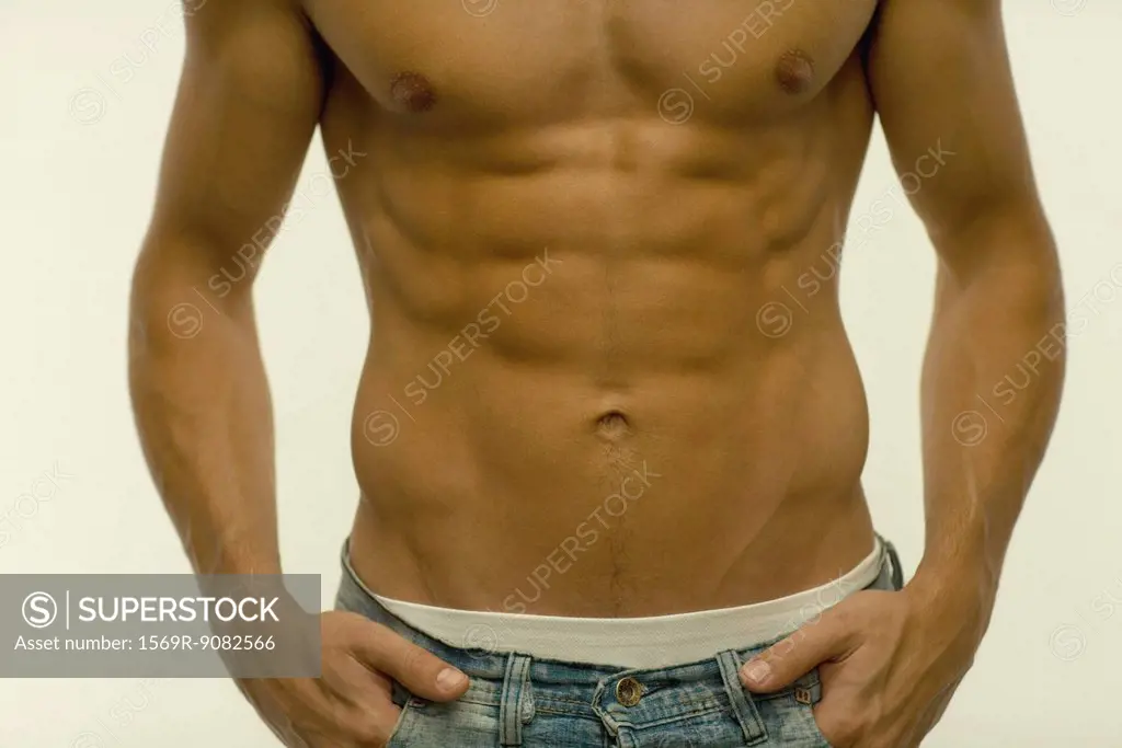 Barechested man with hands in pockets, mid section