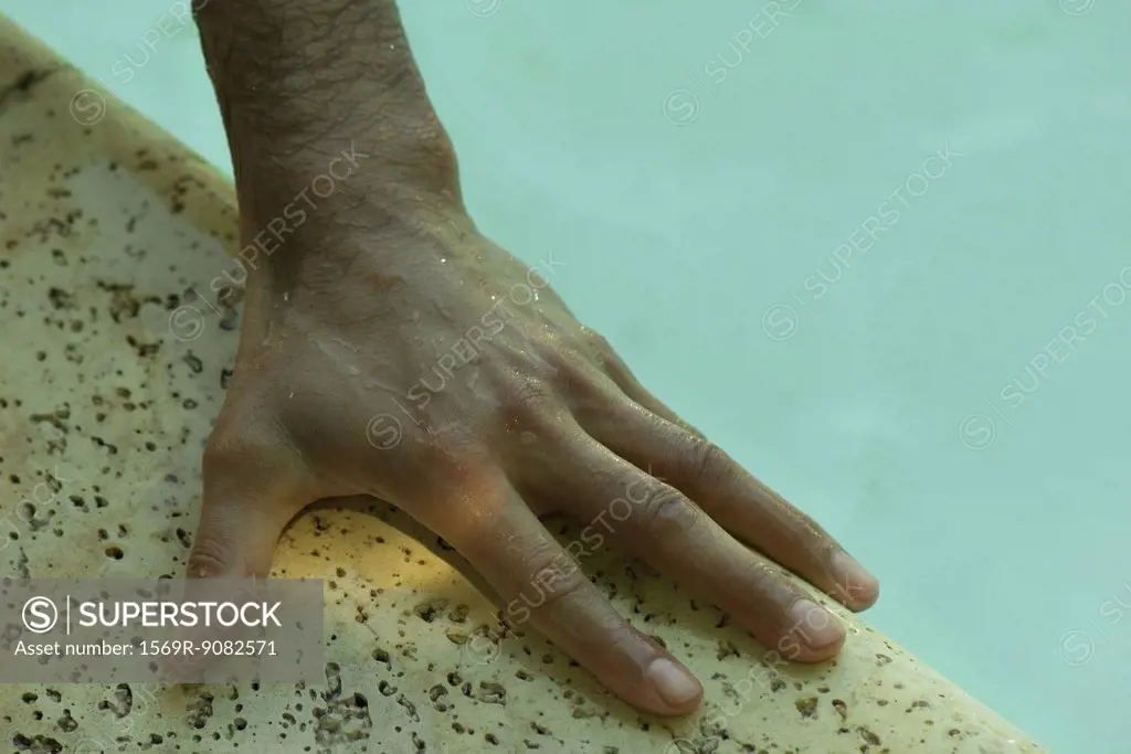 Man's wet hand on side of pool