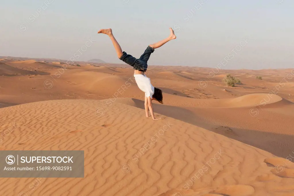 Teenage boy doing handstand in desert