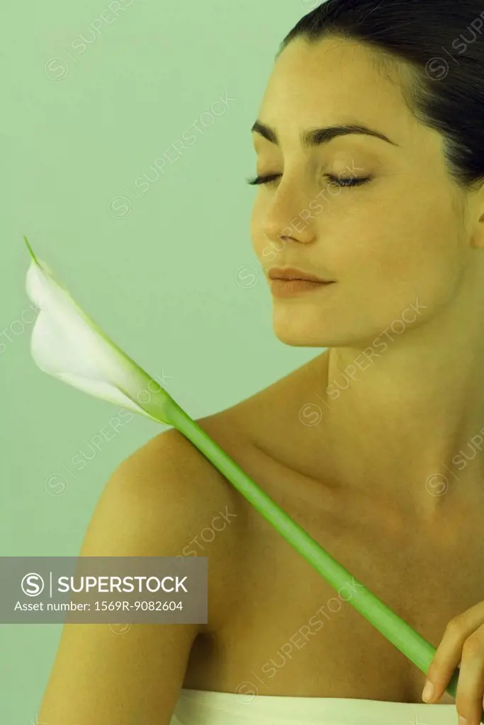 Young woman holding calla lily, eyes closed