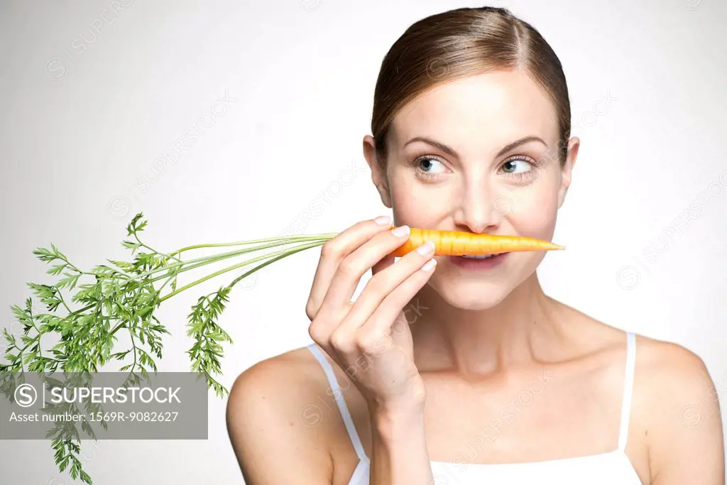 Young woman smelling carrot