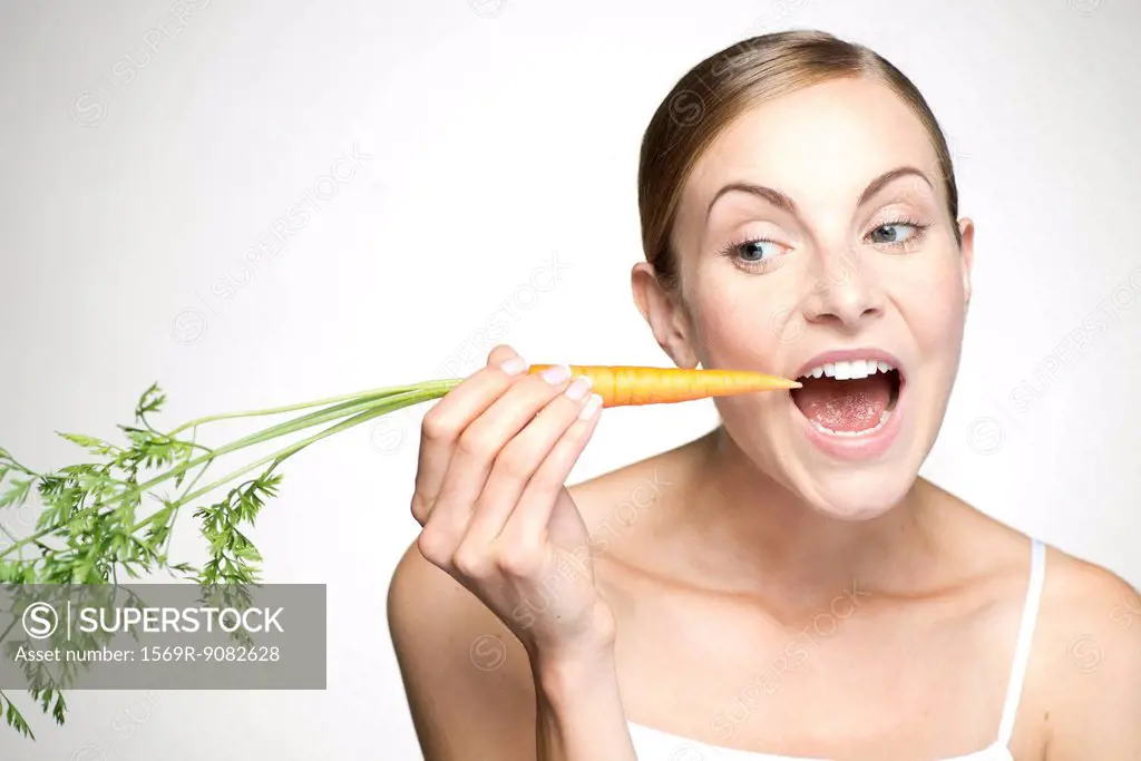 Young woman eating carrot