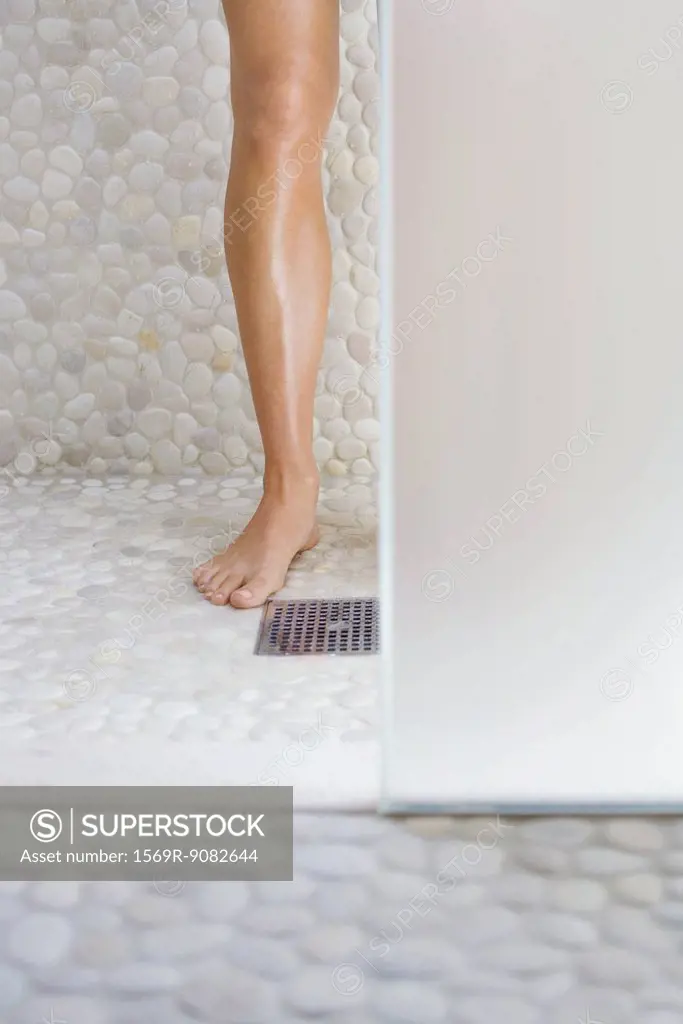 Woman standing in shower, cropped view of one leg