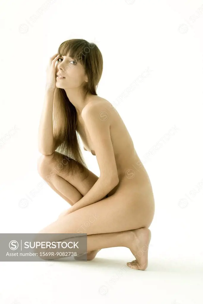 Nude young woman kneeling, looking at camera