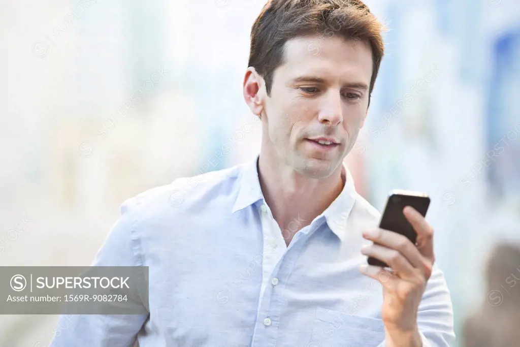 Mid-adult man checking cell phone, portrait