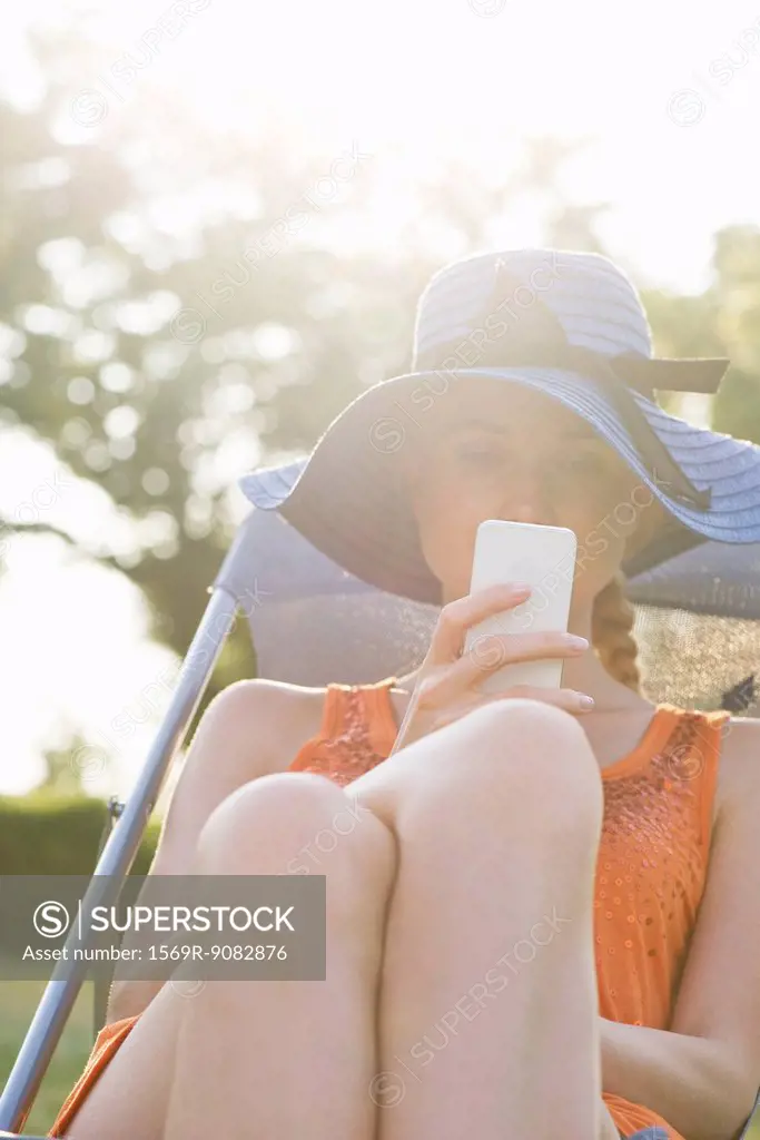 Young woman relaxing outdoors with smartphone