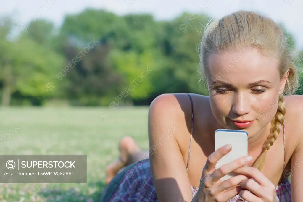 Woman lying on grass using smartphone