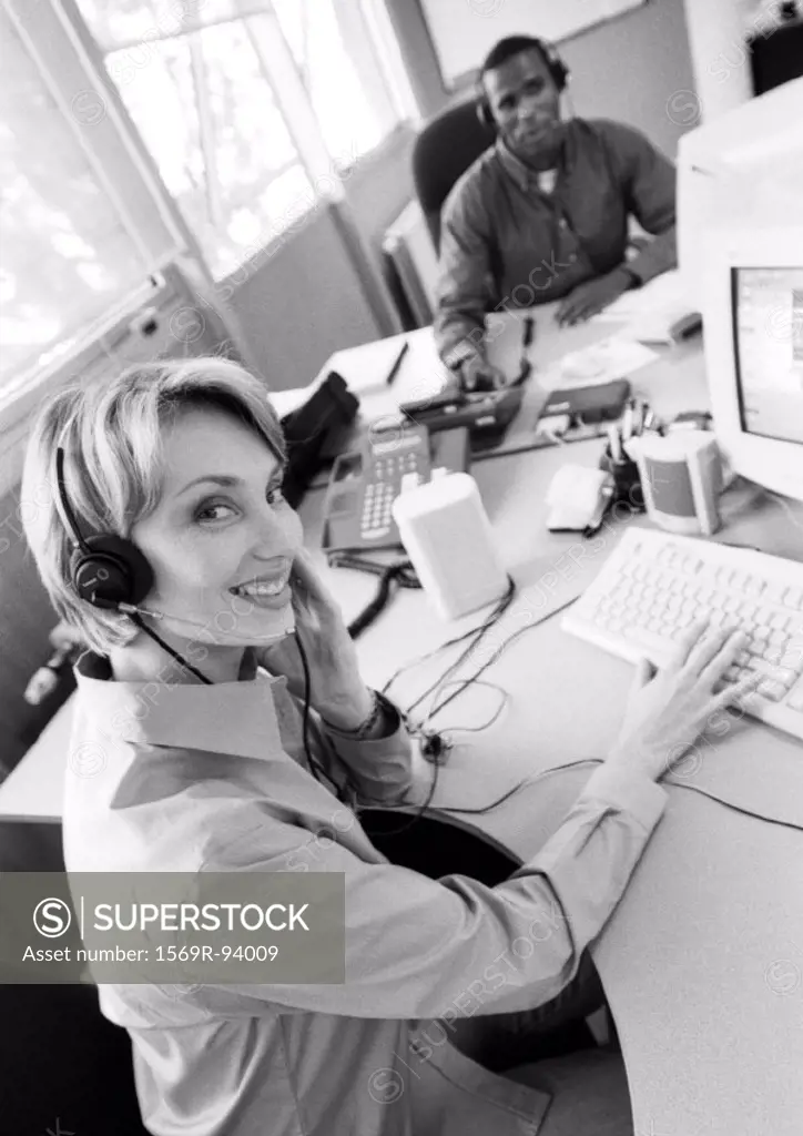 Businesswoman and colleague wearing headsets, B&W