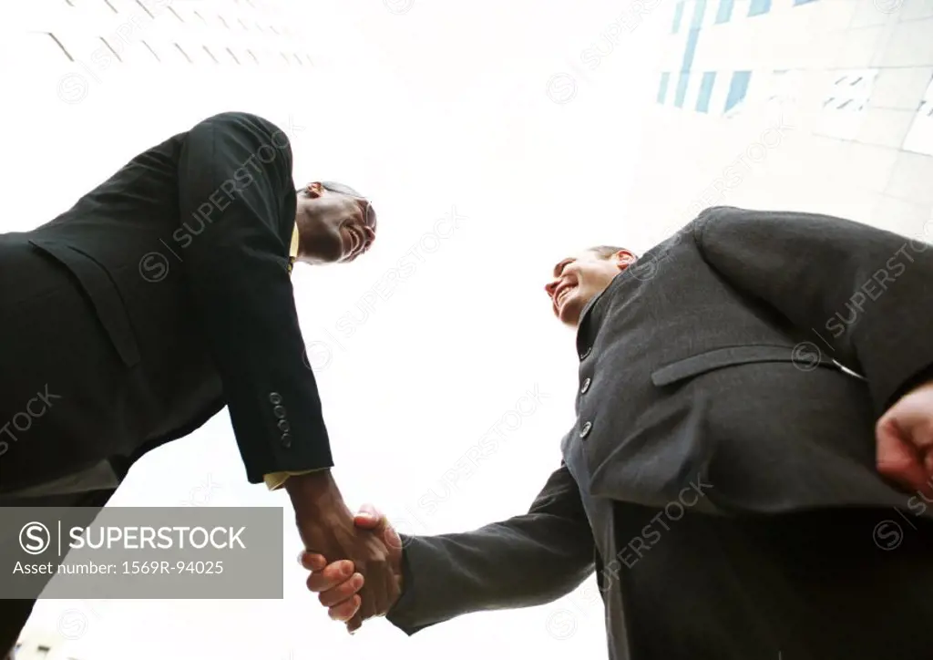 Two businessmen shaking hands, low angle view