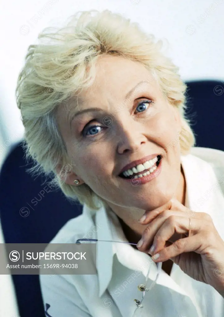 Businesswoman holding glasses, smiling at camera, portrait