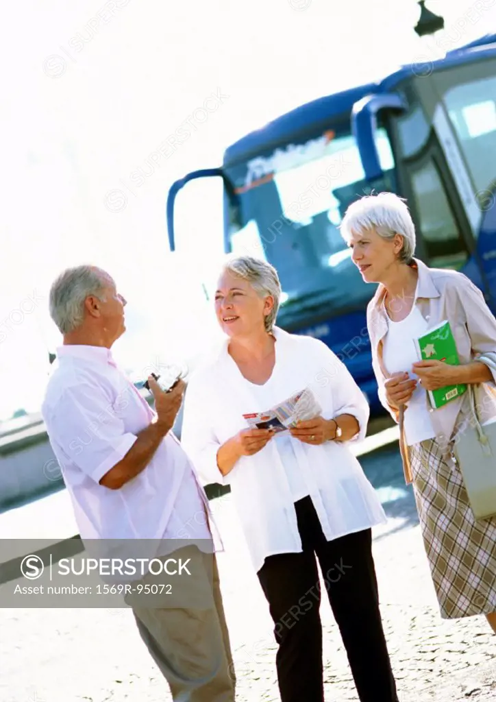 Mature women and man talking in front of a tour bus