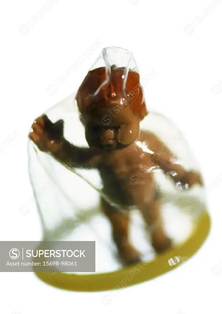 Plastic baby doll standing under condom, close-up