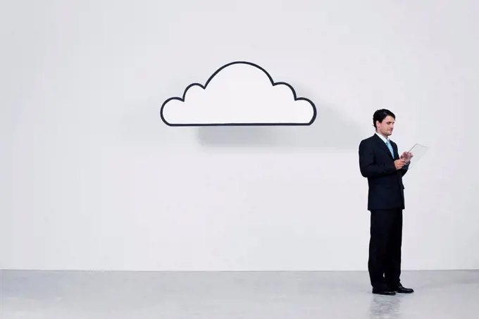 Businessman using digital tablet beneath cloud representing cloud computing