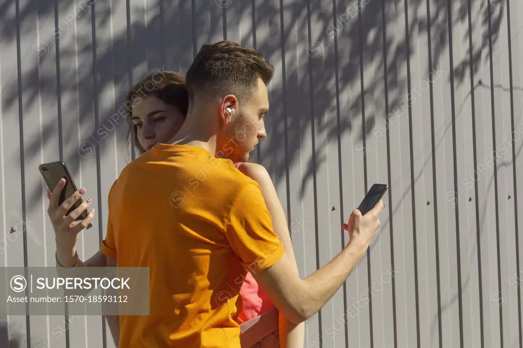 Couple hugging and using smart phones