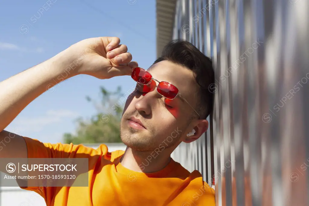 Serene young man removing sunglasses