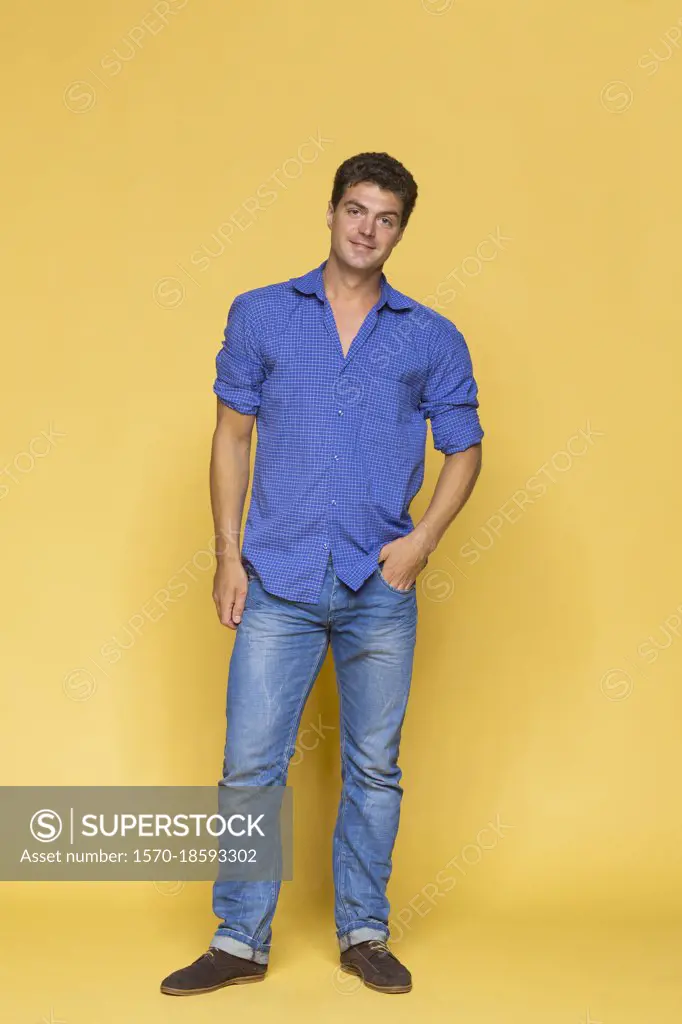 Portrait confident man in blue against yellow background