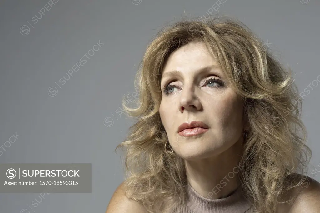 Portrait thoughtful woman looking away on gray background