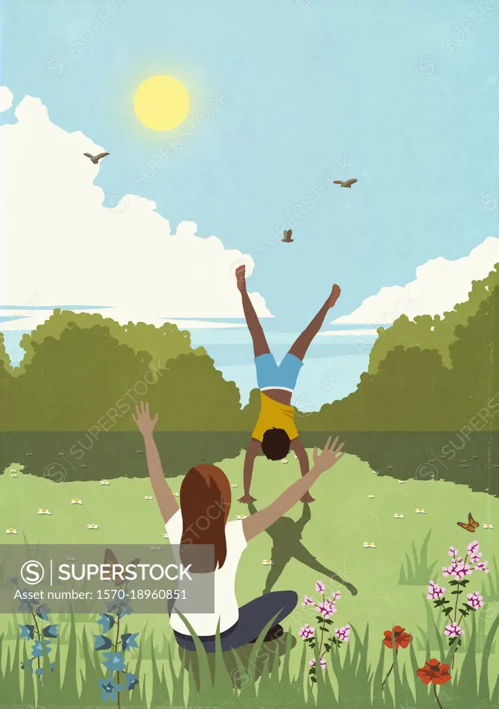 Woman cheering for man doing handstand in sunny, idyllic springtime meadow