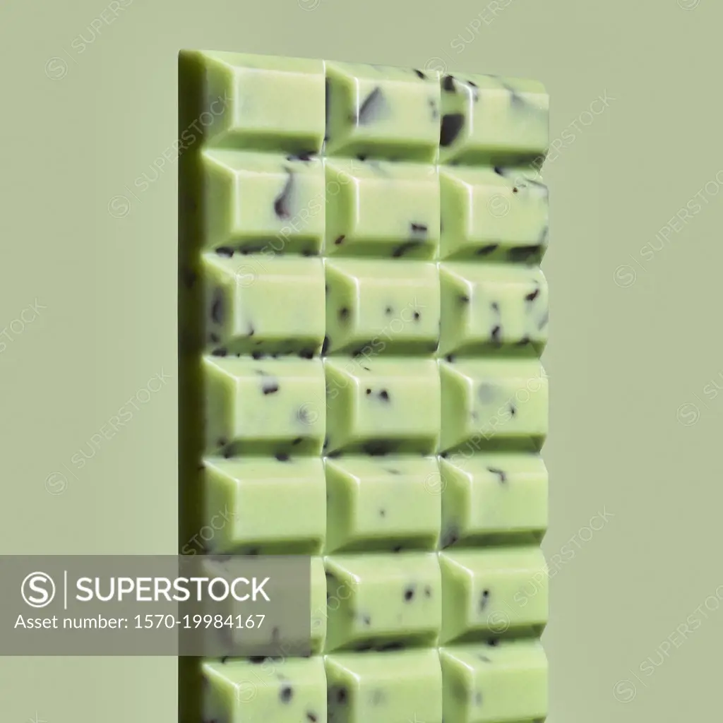Close up green mint chocolate chip candy bar on green background