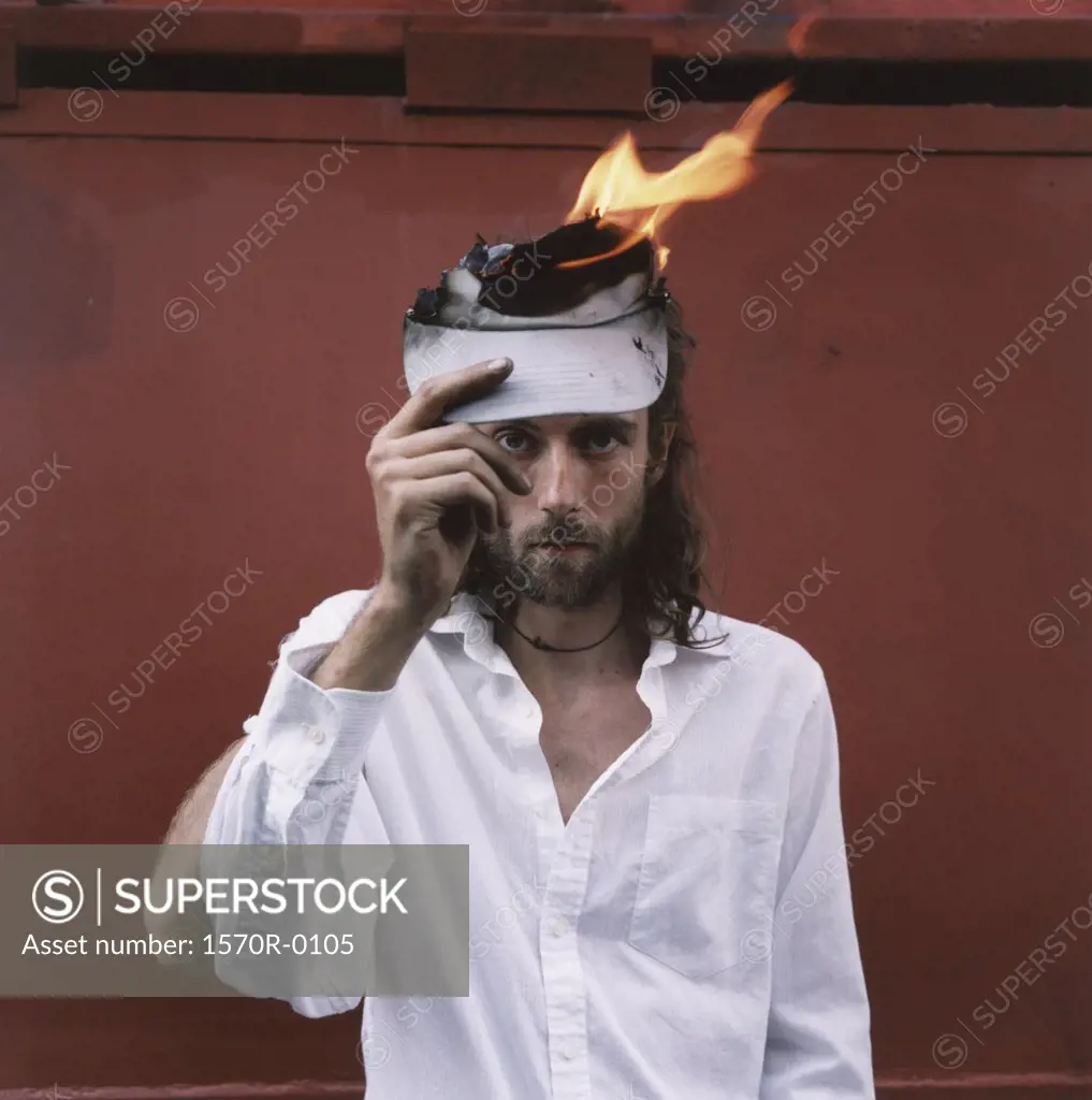 A man with a white shirt holding a piece of paper on fire