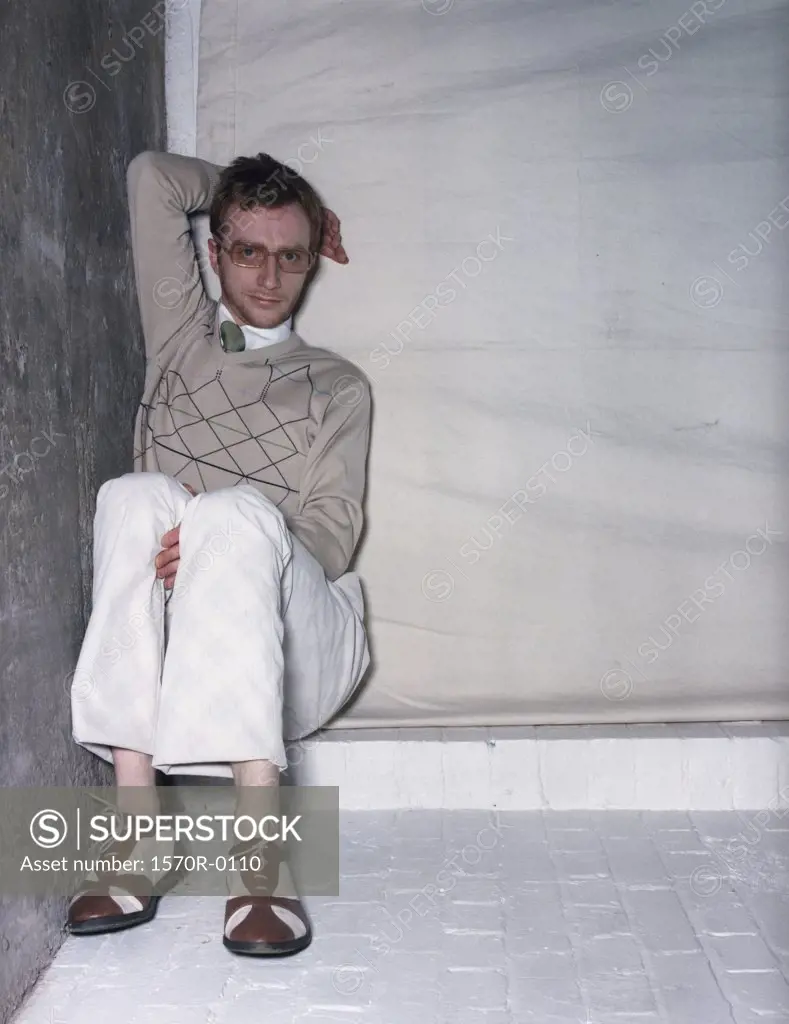 A man sitting in a corner, leaning against the wall