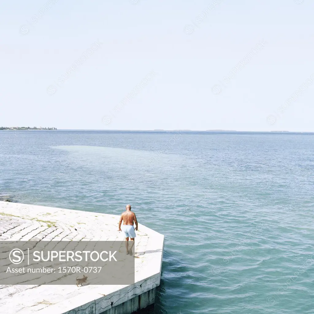 Man walking dog by water's edge, Florida, USA