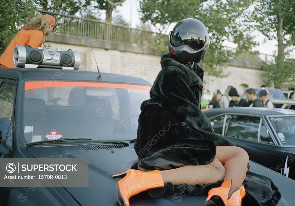 A woman posing on a car hood