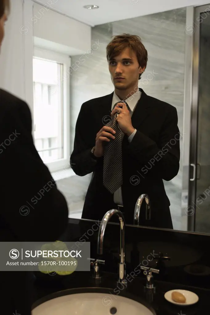 Man tying his necktie in the mirror