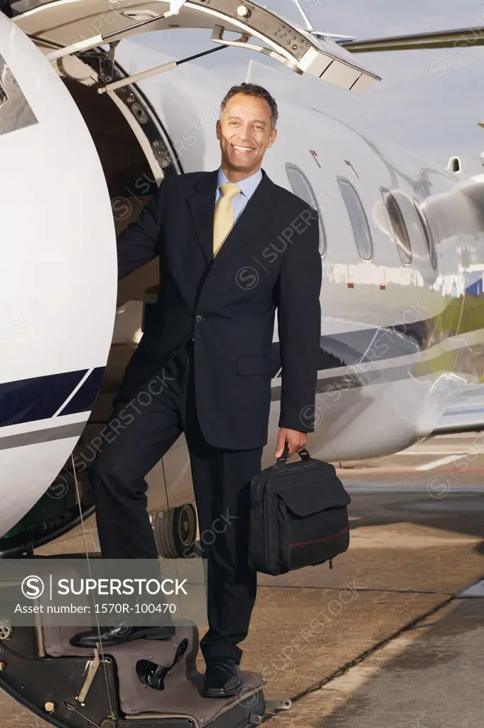Businessman standing on private airplanes steps