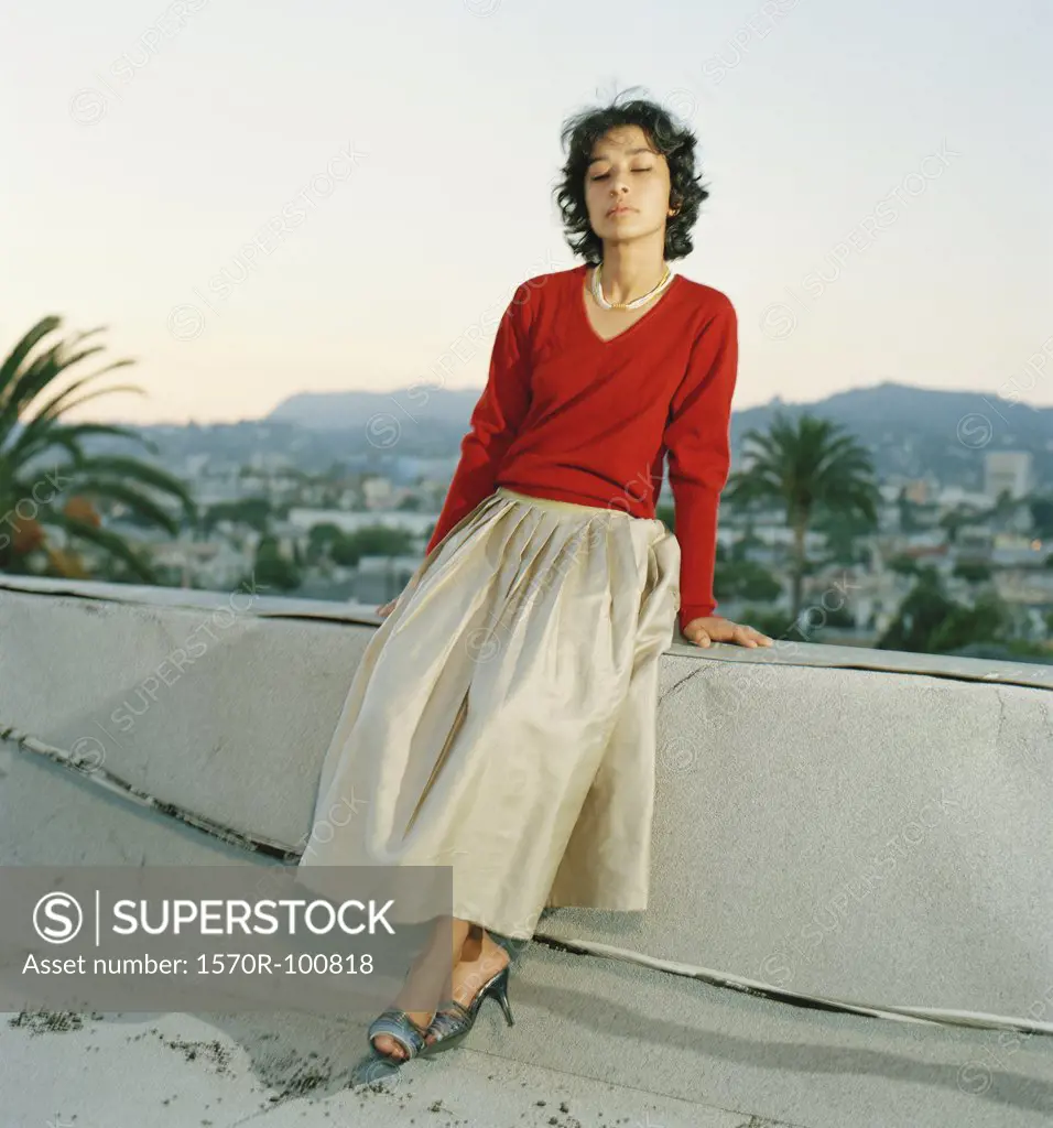 Woman sitting on ledge with eyes closed