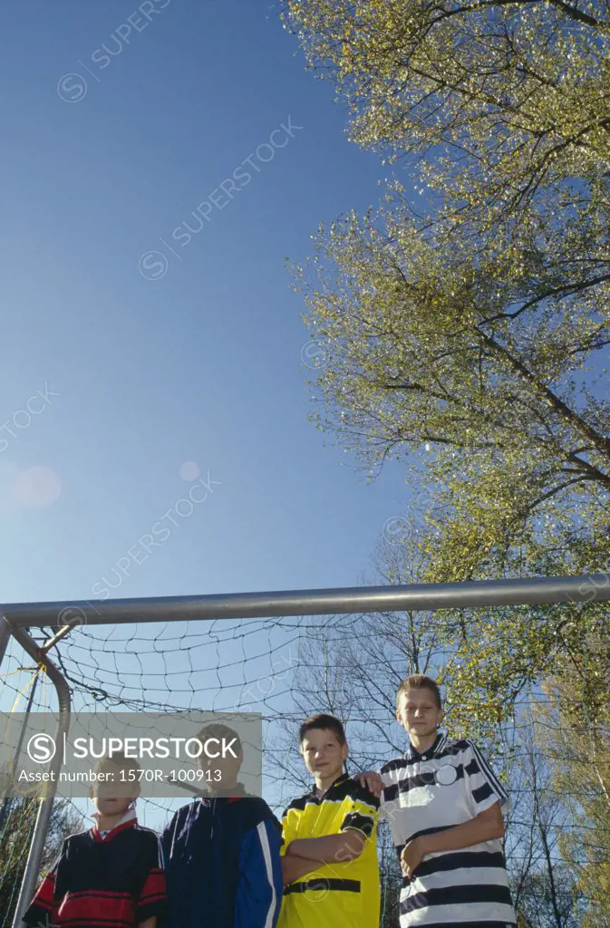 A group of boys standing in a soccer goal