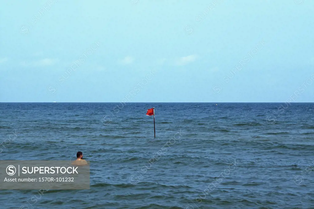 A man in the ocean near a buoy