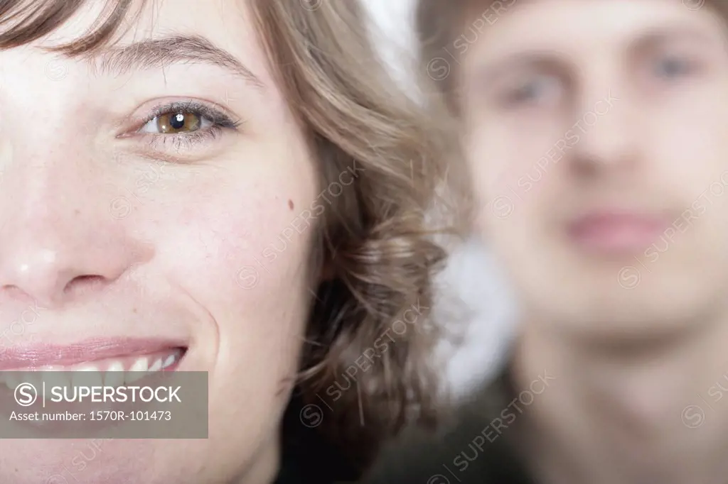 Close up of a young woman with a man blurred in the background