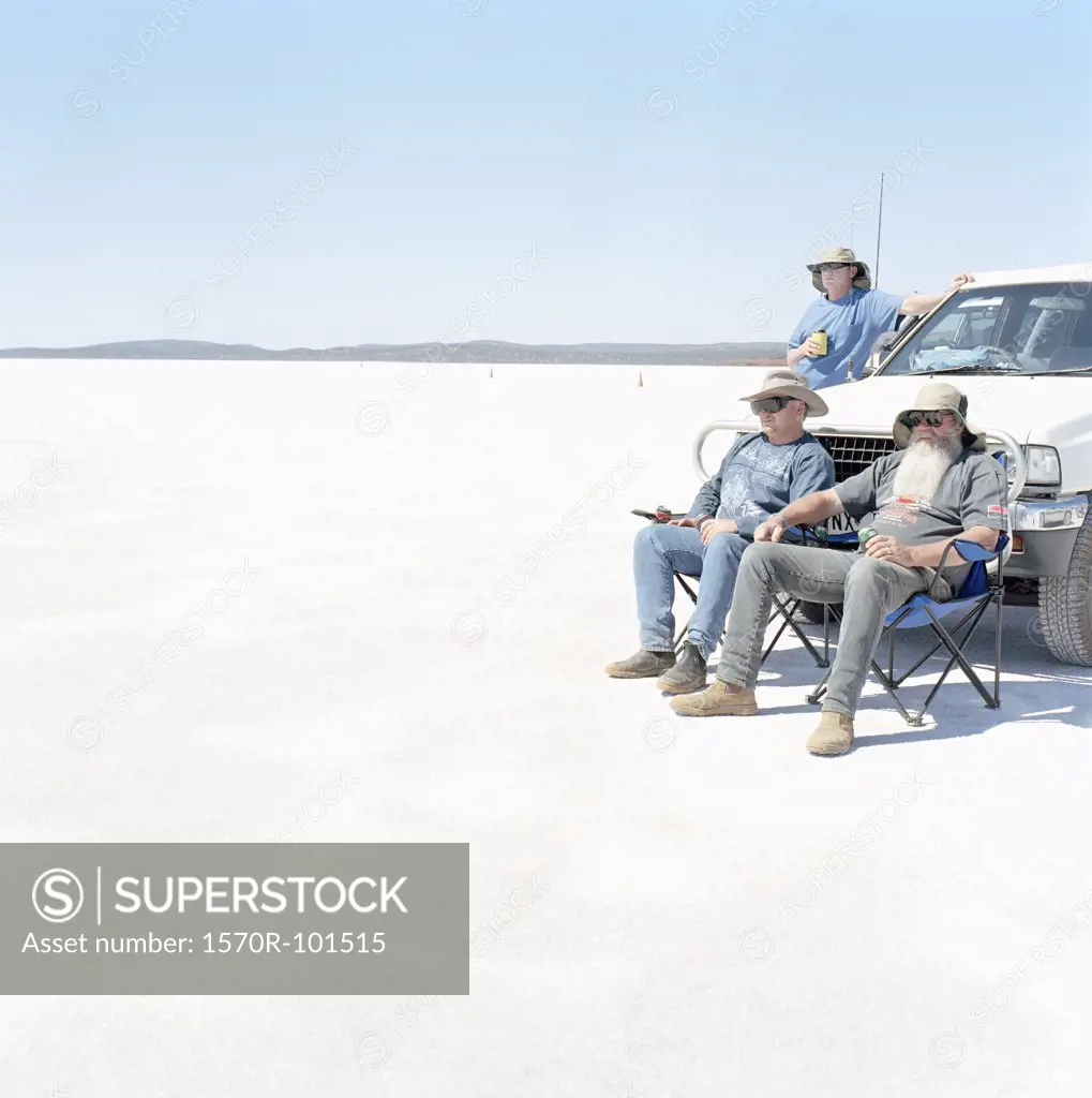 Three men and a car in a desert