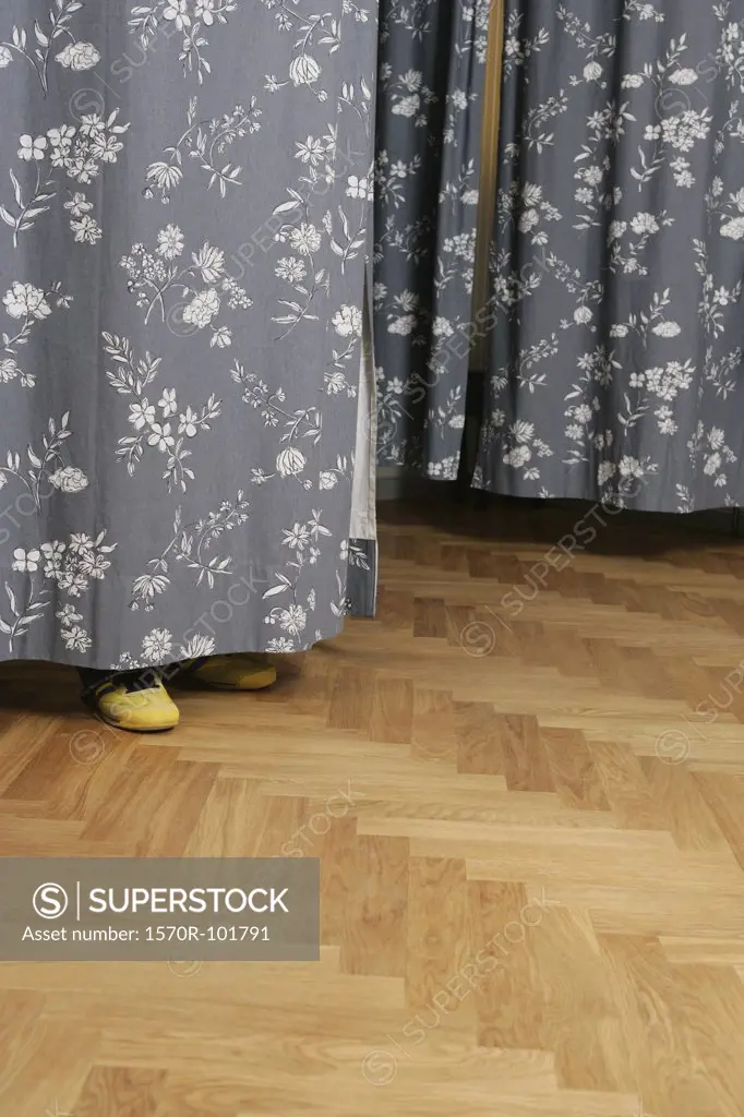 Side view of human feet beneath a dressing room curtain