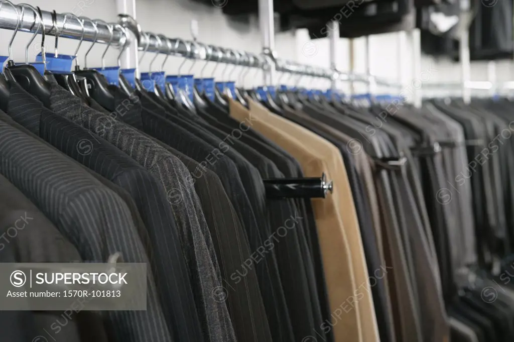 A large number of suits on a clothing store rack