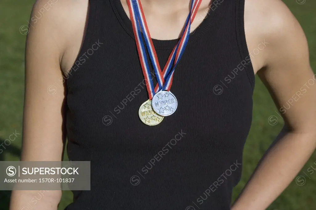 Midsection of a young woman wearing gold and silver medals