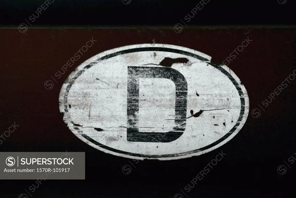 An old sticker with the letter D on a wall