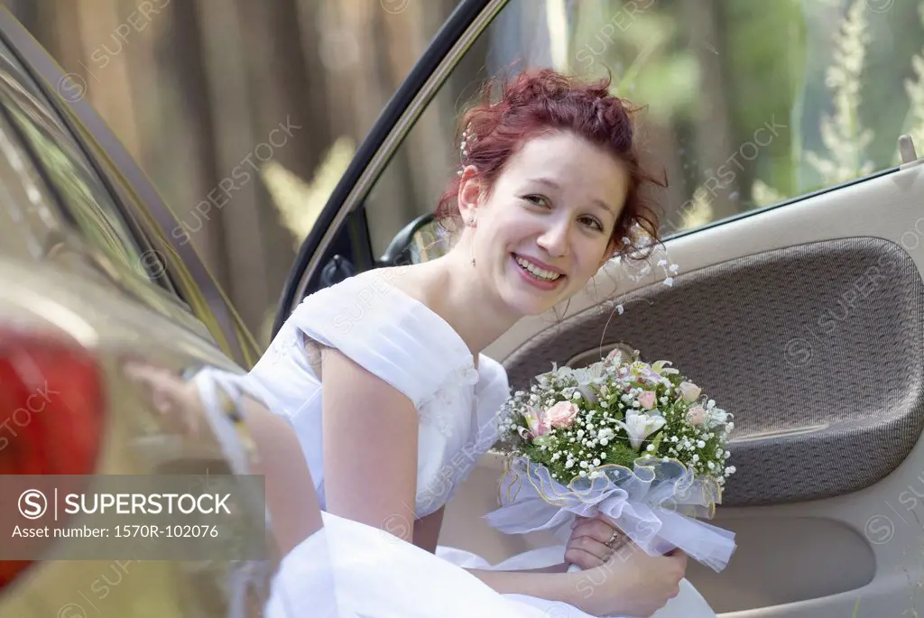 A bride holding a bouquet while sitting in a car