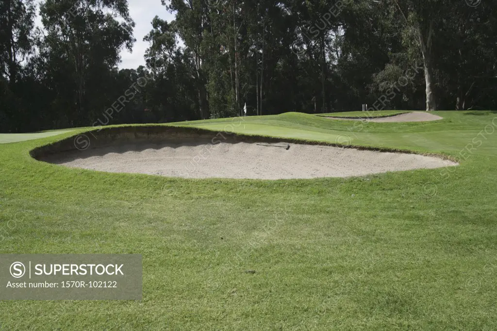 A sand trap in front of a green on a golf course