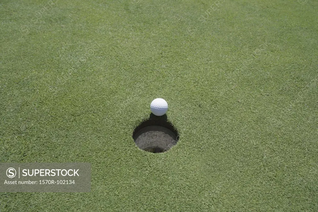 High angle view of a golf ball at the edge of the hole