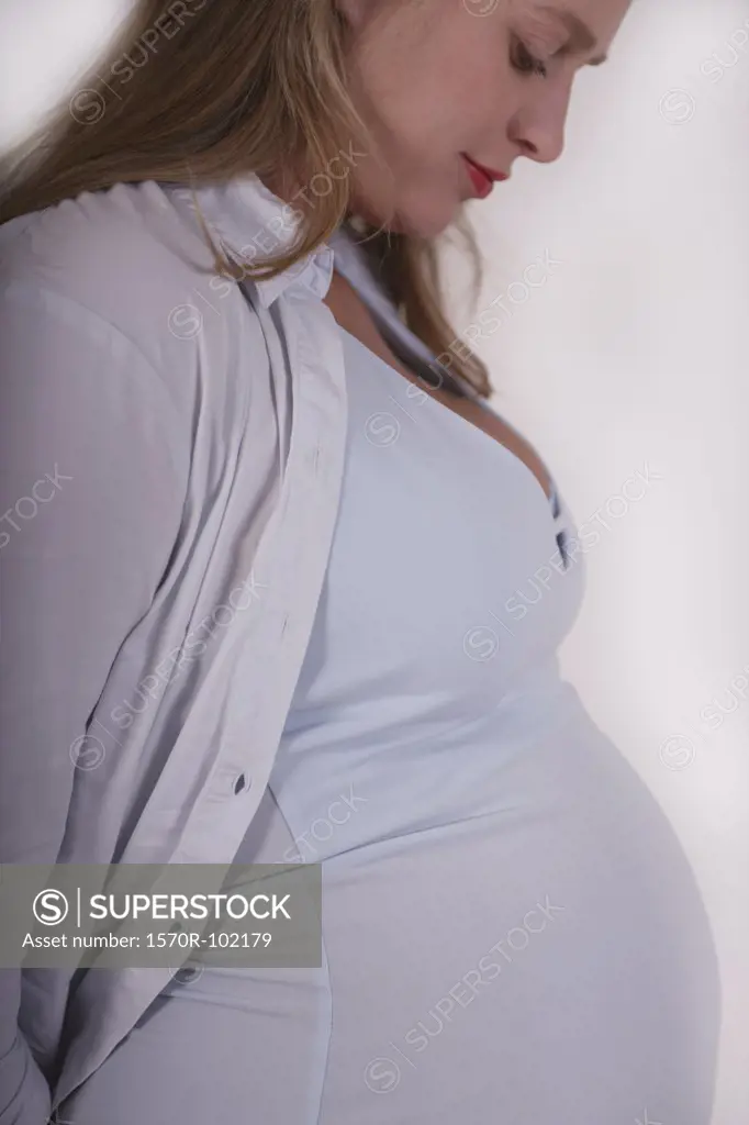 A pregnant woman smiling as she looks at her stomach