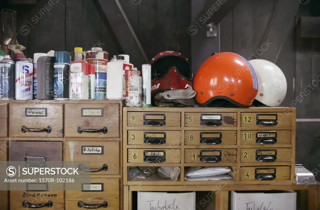 Bottles and helmets arranged above wooden drawers