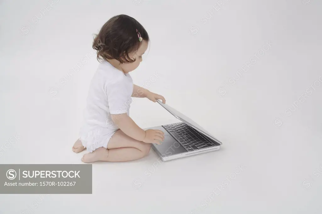 A baby playing with a laptop