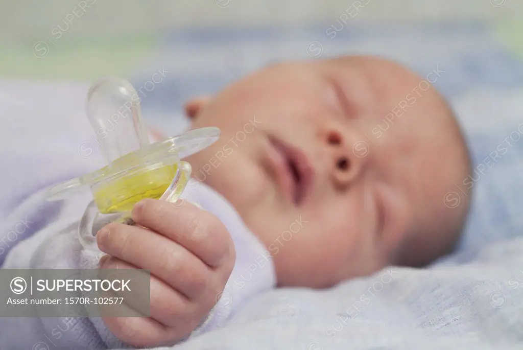 Newborn baby sleeping and holding pacifier