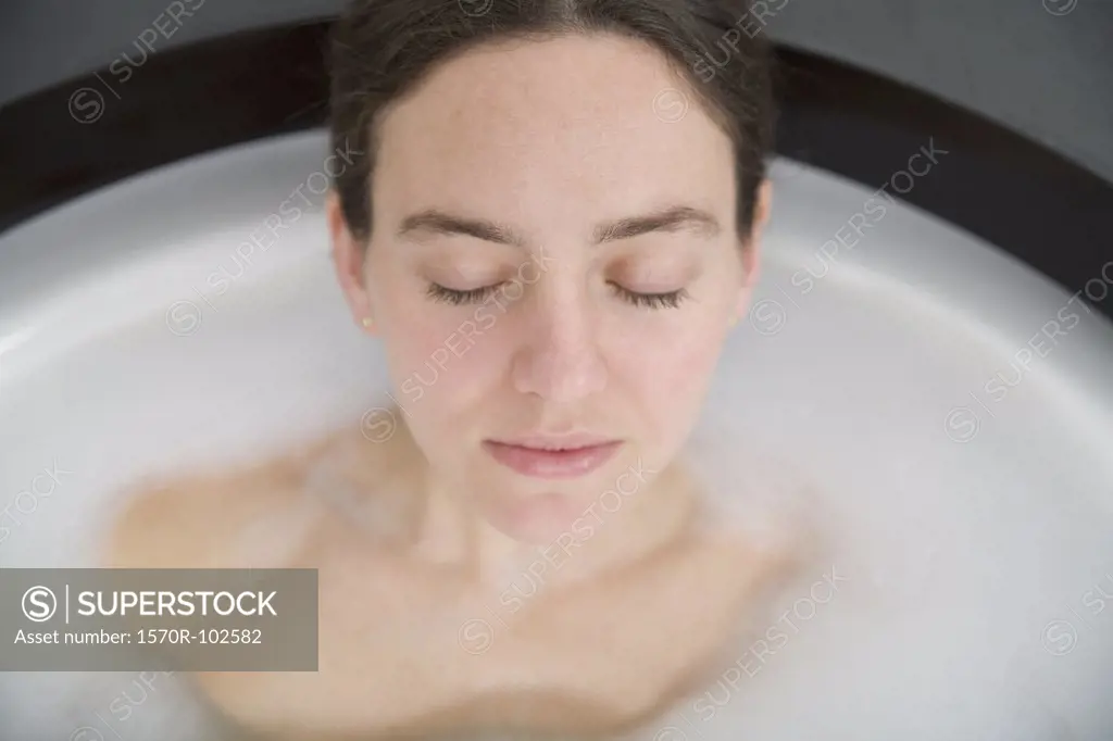 Woman with brown hair lying in bathtub