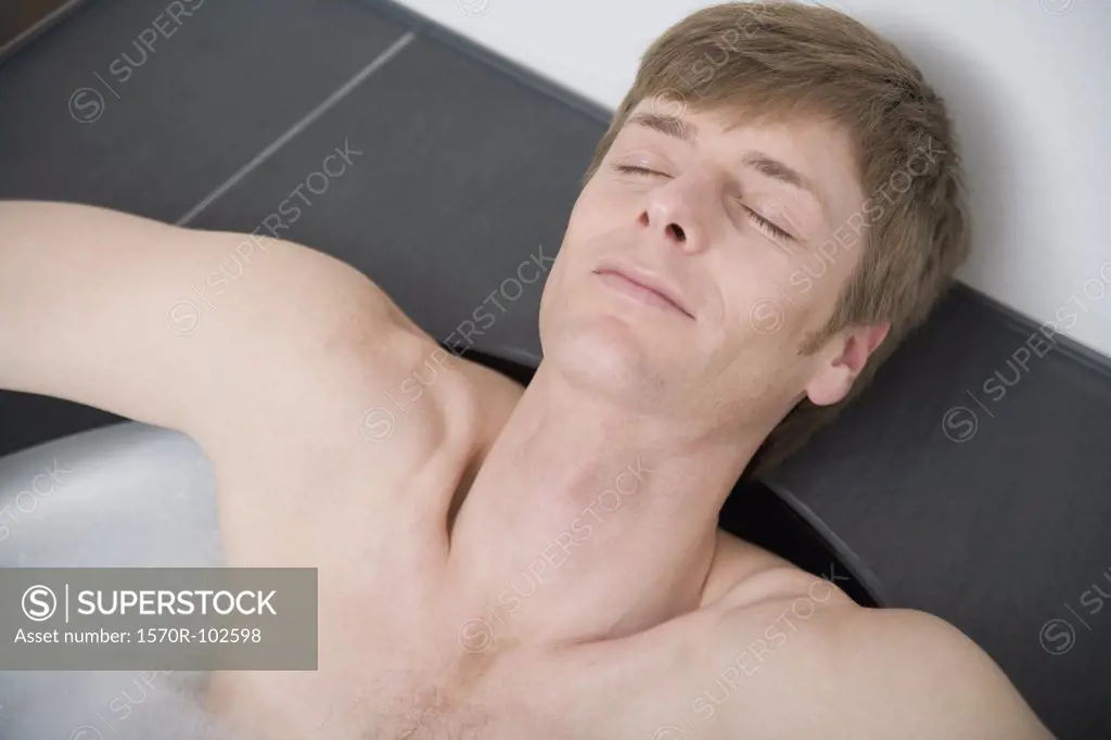Man lying in bathtub with eyes closed