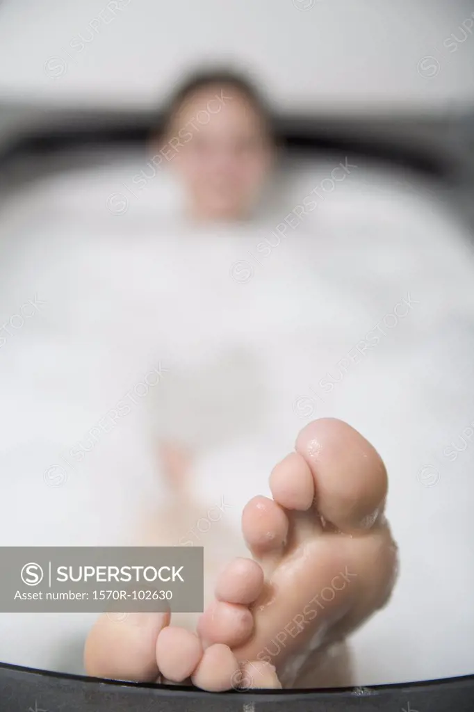 Woman lying in bathtub with feet resting on the edge